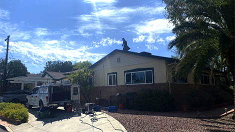 Team cleaning gutters on a slanted roof in Tucson